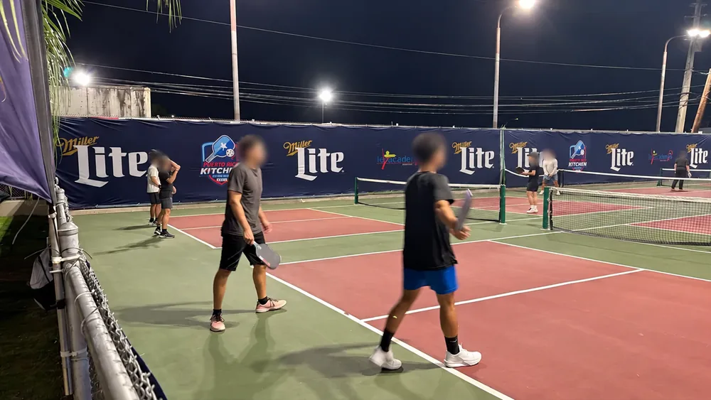 Custom pickleball court fence banners displayed under nighttime lighting
